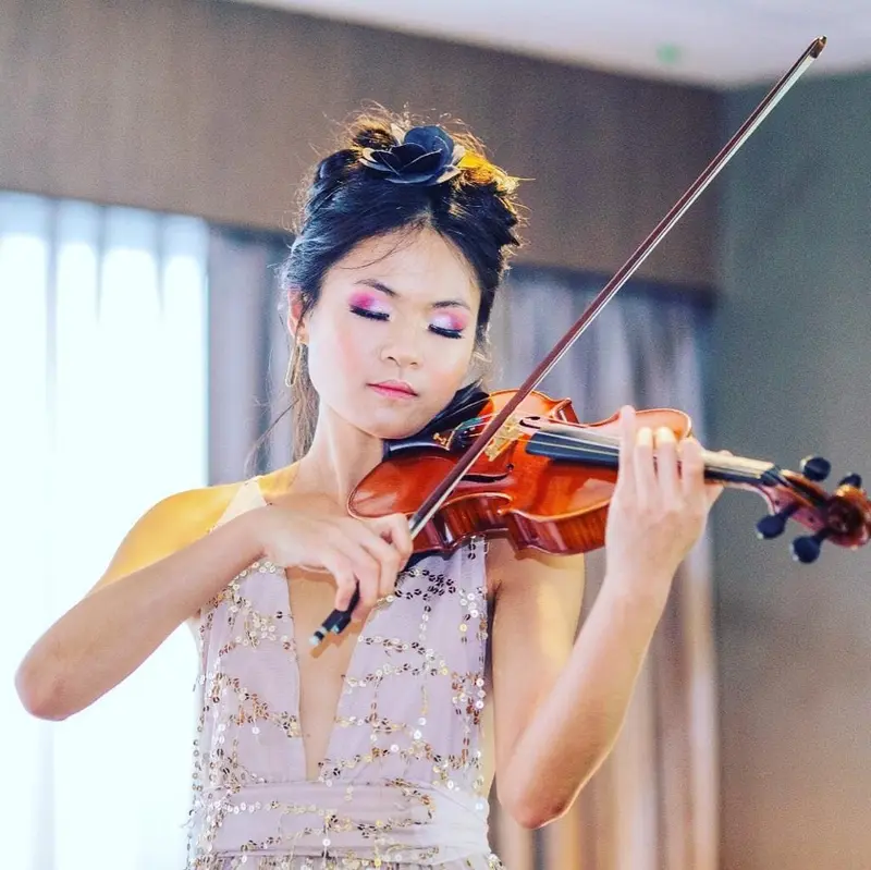 Violinist in a sequinned gown playing a solo with her eyes closed